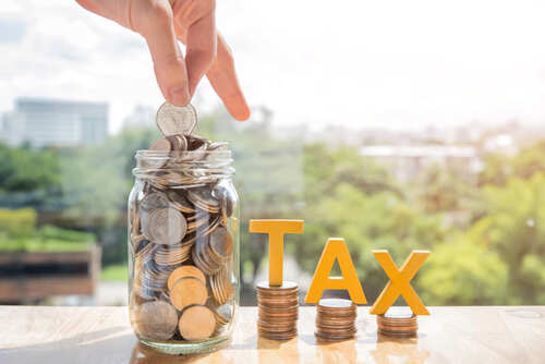 Tax,Concept.word,Tax,With,Stacked,Coins,And,The,Hands,Are