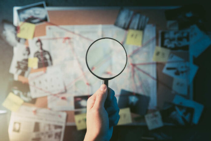Detective,Hand,Holding,A,Magnifying,Glass,In,Front,Of,A