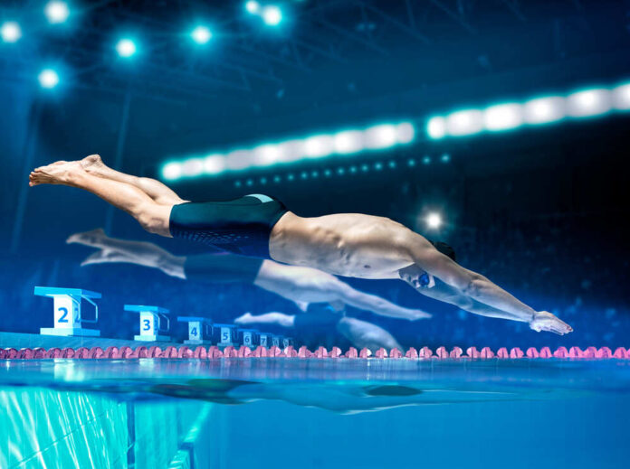 Professional,Young,Muscular,Swimmer,Jumping,From,Starting,Block,In,A