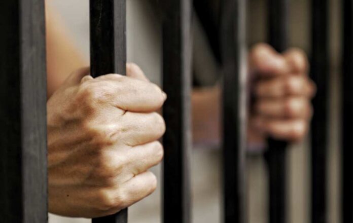 Hands,Of,Prisoner,Holding,Black,Metal,Bars,,Criminal,Locked,In