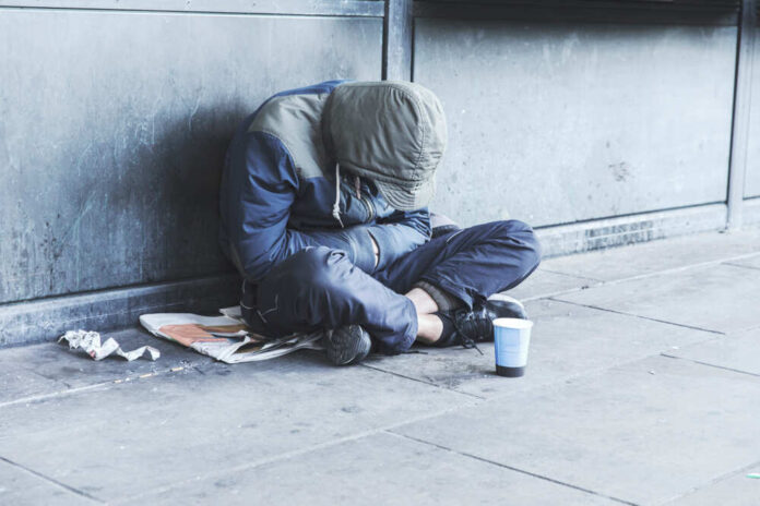Homeless,Man,Sitting,On,The,Street,In,The,Shadow,Of