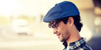 Man with cap using smartphone outdoors, smiling.