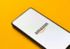 Smartphone displaying Amazon logo on yellow background