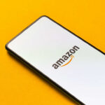 Smartphone displaying Amazon logo on yellow background