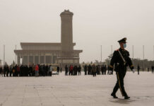 A military guard walking past a crowd at Tiananmen Square in foggy conditions