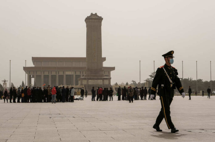 shutterstock_1945568467.jpg A military guard walking past a crowd at Tiananmen Square in foggy conditions