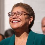 Mayor’s Pothole Stunt Explodes on Live TV A woman with glasses smiling joyfully at an outdoor event