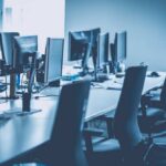 An empty office workspace with multiple computer monitors and chairs