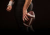 Football player holding a football in hand.