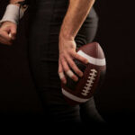 Football player holding a football in hand.