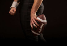 Football player holding a football in hand.