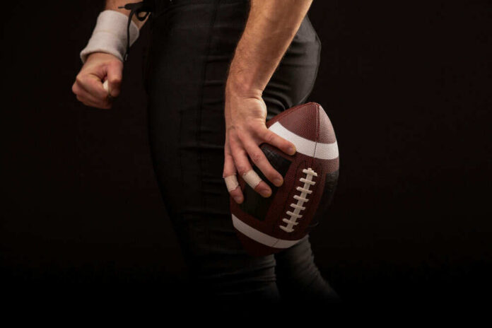 Football player holding a football in hand.