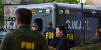 FBI and SWAT team gathered near vehicle.