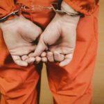 Person in orange jumpsuit handcuffed from behind