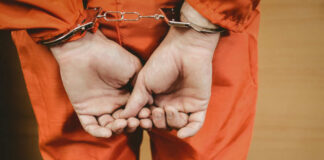 Person in orange jumpsuit handcuffed from behind