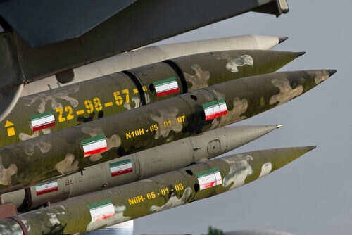 Camouflaged missiles with flag decals mounted on display.
