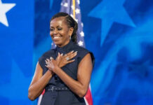 Person standing in front of American flag smiling