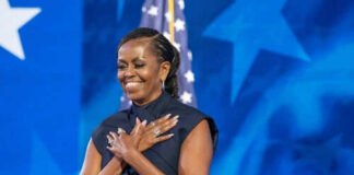 Person standing in front of American flag smiling