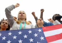 People raising fists with American flag nearby.