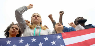 People raising fists with American flag nearby.