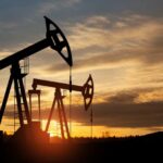 Silhouetted oil pumps against a colorful sunset sky