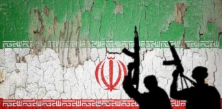 Silhouettes of armed figures in front of a distressed Iranian flag