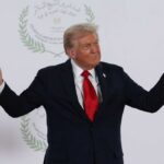 A political figure gesturing with hands during a public appearance