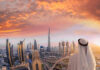 Lightning Bolt Strikes Burj Khalifa – Viral Chaos! A person in traditional attire overlooking the Dubai skyline at sunset