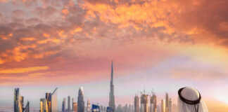 A person in traditional attire overlooking the Dubai skyline at sunset