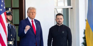 Two men standing outdoors near flags and doorway