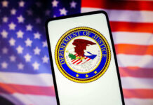 Department of Justice seal on phone, American flag background.