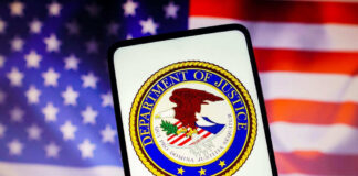 Department of Justice seal on phone, American flag background.