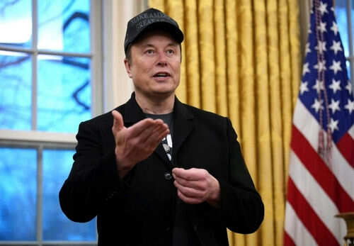 Man wearing hat gesturing in room with flag