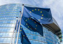 European Union flags waving outside glass building