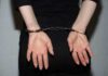 A teenagers hands are cuffed behind their back with silver handcuffs