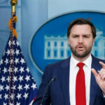 Man speaking at podium with US flag behind