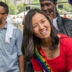 Person wearing rainbow sash smiling at event