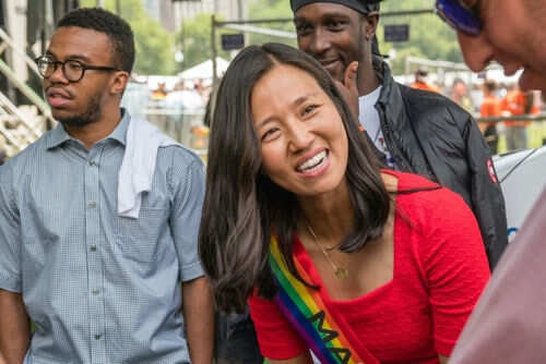 Person wearing rainbow sash smiling at event