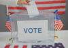 Hand placing ballot in box with American flags