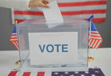 Hand placing ballot in box with American flags
