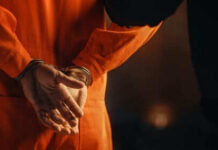 Person in orange jumpsuit with hands cuffed behind back