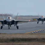 Two F-35 fighter jets on an airfield preparing for takeoff