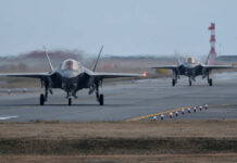 Two F-35 fighter jets on an airfield preparing for takeoff