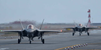 Two F-35 fighter jets on an airfield preparing for takeoff