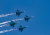 Four military jets flying in formation with smoke trails against a blue sky