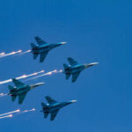 Pakistani Fighter Jets DEPLOYED — Iran Threat Escalates Four military jets flying in formation with smoke trails against a blue sky