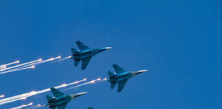 Four military jets flying in formation with smoke trails against a blue sky