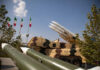 Military missiles displayed outdoors with Iranian flags in the background