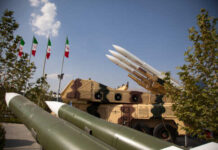 Military missiles displayed outdoors with Iranian flags in the background