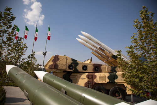 Military missiles displayed outdoors with Iranian flags in the background